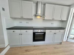 a kitchen with white cabinets and a black counter top at Cosy stylish house West Hull in Hull