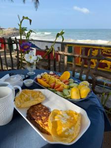 a table with a plate of food on a table with the beach at Blue Maalu Resort in Ambalangoda