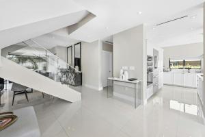 a white kitchen with a staircase and a dining room at Villa Sienna Coastal Warmth in Hollywood