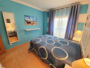 a bedroom with a bed in a room with blue walls at Casa T2 in Monte Gordo