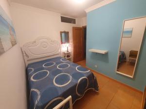 a bedroom with a bed with a blue comforter and a mirror at Casa T2 in Monte Gordo