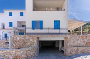 a large white building with blue doors and a garage at Apartment Blue Monstéra in Cres
