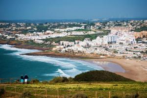 two people standing on a hill overlooking a beach at A28 - Castela Street Townhouse in Espiche in Luz