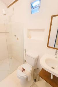 a white bathroom with a toilet and a sink at Pousada Vilarejo in Caraíva