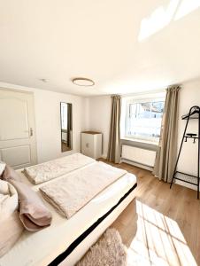 a white bedroom with a large bed and a window at Auszeit zwischen Mosel und Nürburgring in Kehrig