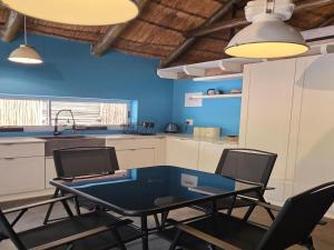 a kitchen with blue walls and a table and chairs at Little Orvyll's in Marloth Park