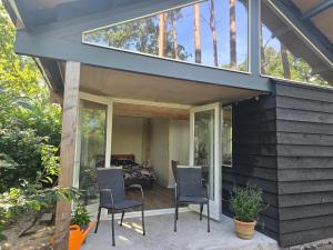 a house with glass doors and chairs on a patio at Studio de Vretberg in Enschede