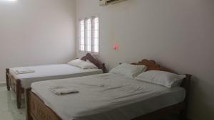 two twin beds in a room with a window at Aala Stays in Tirunelveli