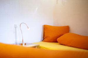 a bed with two orange pillows and a lamp on it at Chasa Ulrica in Ftan