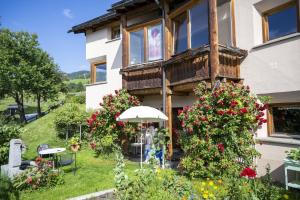 a house with a balcony with flowers in the yard at Chasa Ulrica in Ftan