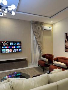 a living room with a couch and two chairs and a tv at Crystal's apartment in a secure estate with pool in Ibeju