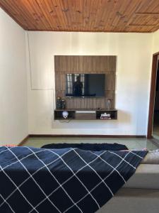 une chambre avec un lit et une télévision sur un mur dans l'établissement Casa Paiol Grande, à São Bento do Sapucaí