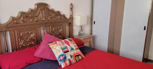 a bed with a wooden headboard and two pillows at Anaga Tucho Natural Beach House in Santa Cruz de Tenerife