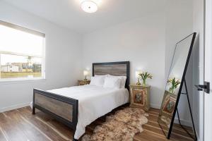 a white bedroom with a bed and a mirror at The Railway Flats 102 in Missoula