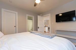 a bedroom with a white bed and a flat screen tv at Slant Streets Bungalow in Missoula
