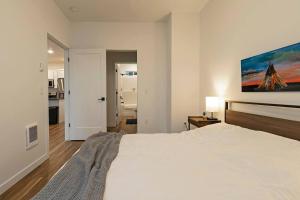 a bedroom with a large white bed with a painting on the wall at The Railway Flats 101 in Missoula