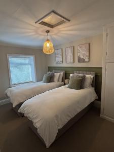 2 Betten in einem Schlafzimmer mit Kronleuchter in der Unterkunft Sunset Cottage - 55 South Lane in Holmfirth