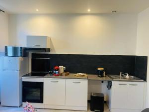 a kitchen with white cabinets and a black wall at Charmant T2 centre ville N 4 in Marmande +3 photos