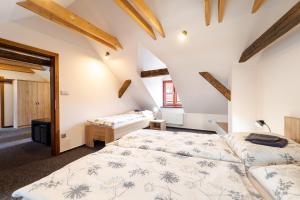two beds in a room with white walls and wooden beams at Pivovar Prachatice in Prachatice +55 photos