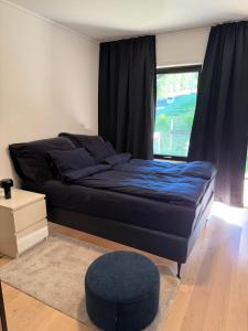 a bedroom with a bed with a blue comforter and a window at Nordheim Aparment in Tromsø