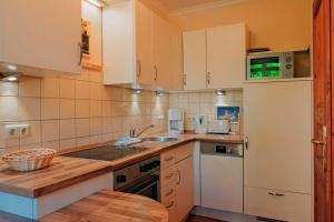 a kitchen with white cabinets and a sink and a refrigerator at Residenz-Seestern-Whg-31 in Kühlungsborn