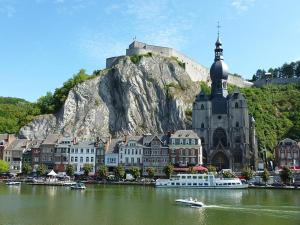 a large building with a church next to a body of water at Studio 50m from the Citadel in Dinant