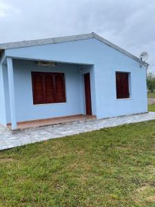 a white house with red windows and a yard at Complejo Juan Pablo in Colón