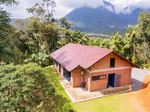 a house with a red roof with a mountain in the background at Sitio Dona Bela - Rio da Prata in Joinville