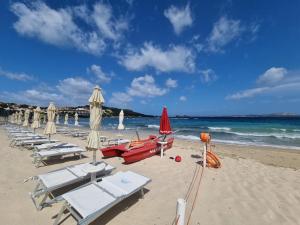 een strand met ligstoelen en parasols en de oceaan bij Rena Bianca Residence 225 in Baja Sardinia
