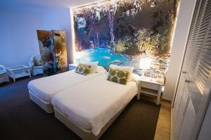 a room with two beds and a painting on the wall at Lago Garden Apart-Suites & Spa Hotel in Cala Ratjada +130 photos