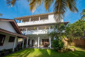 an exterior view of a white house with a yard at Sweet Emotion in Mirissa