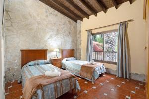 una camera da letto con due letti e un muro di pietra di Los Nardos a Montijos