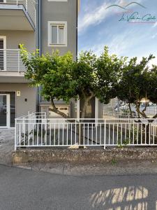 a white fence in front of a building with trees at La valle del ciglioto in Licusati