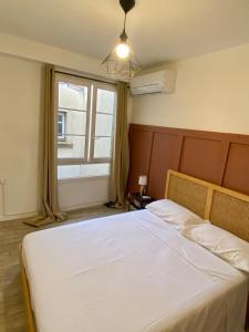 a bedroom with a large white bed with a window at Les Halles d'Isa et Thomas in Narbonne +5 photos