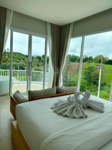 ein Bett mit einem Handtuch in einem Zimmer mit Fenstern in der Unterkunft Hill Jai Poolvilla Khao Kho in Khao Kho