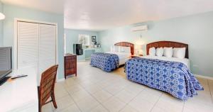 a bedroom with two beds with blue and white sheets at Creekside Inn in Tavernier