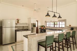 a kitchen with a large island with green chairs at La Morella - 4BHK Luxury Villa in Assagao with Private Pool, Garden, Balcony, Caretaker, Kitchen, Genset Backup, Security in Assagao