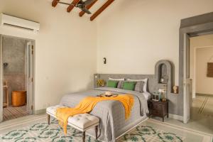 a bedroom with a bed with an orange blanket on it at La Morella - 4BHK Luxury Villa in Assagao with Private Pool, Garden, Balcony, Caretaker, Kitchen, Genset Backup, Security in Assagao