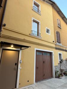 un edificio amarillo con dos puertas y ventanas de garaje en Casa Samy, en Desenzano del Garda