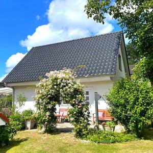 una casa blanca con un arbusto en flor delante de ella en Ferienhaus Karola, en Kolpinsee