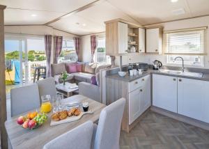 a kitchen and living room with a table and chairs at Trevornick Holiday Park in Cubert