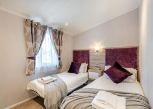 une chambre avec deux lits et une fenêtre dans l'établissement Nunland Hillside Lodges, à Lochfoot