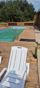 une chaise blanche assise sur une terrasse en bois à côté d'une piscine dans l'établissement Zacisze obok Suntago Park noclegi 2 3 6 osobowe domki, à Grabce 8 autres photos