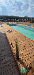 une femme se posant sur une terrasse à côté d'une piscine dans l'établissement Zacisze obok Suntago Park noclegi 2 3 6 osobowe domki, à Grabce