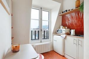 a small kitchen with a white refrigerator and a window at la suite rouge du marais in Paris