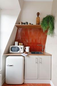 a kitchen with white cabinets and a microwave at la suite rouge du marais in Paris