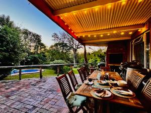 Una mesa y sillas de madera en un patio. en Gorgeous home - 5 minutes from Grahamstown, en Grahamstown