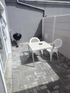 Una mesa blanca y sillas en un patio con parrilla. en Birds Holiday Accommodation 1, en Zeekoevlei