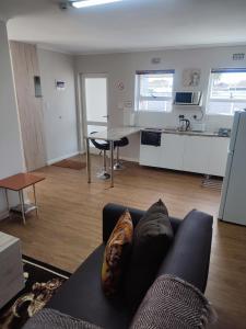 Una sala de estar con un sofá y una cocina. en Birds Holiday Accommodation 1, en Zeekoevlei