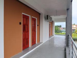 an empty corridor with red doors on a building at KG Hotel in Kampong Sorosob